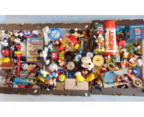 Three boxes of Mickey Mouse merchandise including umbrellas, clocks, games, mug and mat set, small figures, thermos flask, et