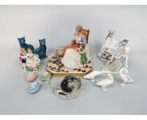 A Lladro figure group of a South American style female character in hat and cloak cradling a child, 24cm tall approx, togethe