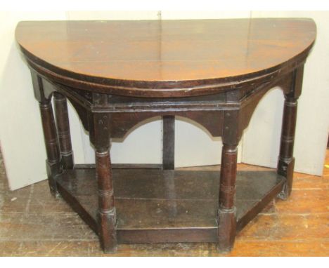 A good early oak credence table, the D end top raised on four gun barrel shaped pillars with simple gateleg action, over and 