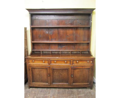 An 18th century oak dresser, the lower section enclosed by three panelled doors and three frieze drawers, the plate rack fitt