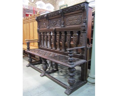 An antique oak settle, the raised and partially panelled back with geometric mouldings, lions mask, cherub and stag hunting s