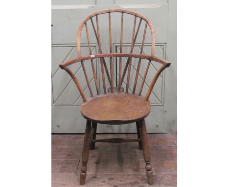 A primitive Windsor stick back elbow chair in mixed woods, the circular seat raised on four turned supports