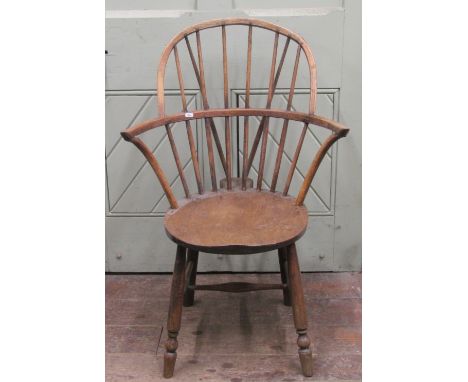 A primitive Windsor stick back elbow chair in mixed woods, the circular seat raised on four turned supports