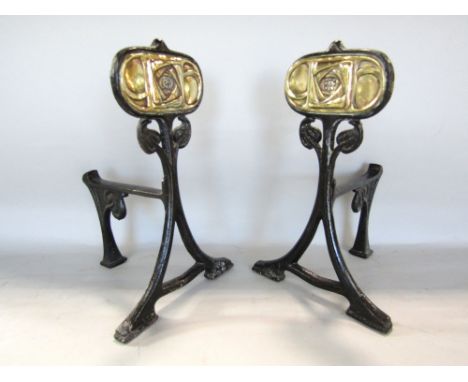 A pair of Art Nouveau cast iron andirons on swept supports with embossed brass plate panels