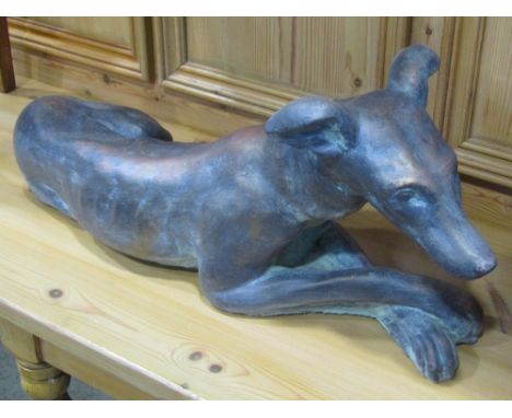 A cast composition recumbent greyhound or whippet to simulate bronze with simulated verdigree finish, 2ft long approx