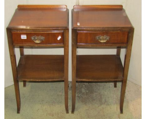 A pair of walnut veneered two tier bedside lamp tables, each fitted with a frieze drawer and raised on square cut and slightl