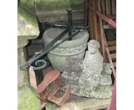 A small weathered novelty cast composition stone garden ornament in the form of a man sitting on a stone bench together with 