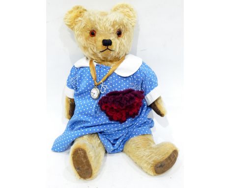 A vintage mohair bear with glass eyes with a fob watch attached 