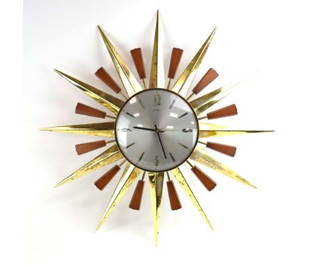 A Metamec 'starburst' or 'sunburst' clock, the plain silvered face with Arabic numerals and surrounded by teak and brass rays