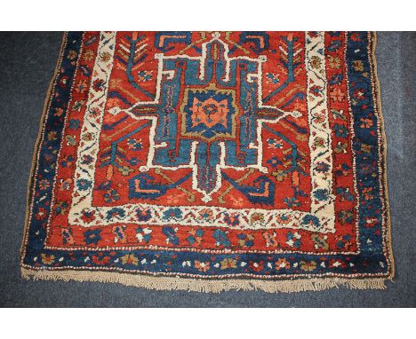 A Persian wool runner carpet with five central geometric motifs within floral multi-line borders, in red, blue and white, 101