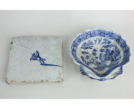 A Delft blue and white wall tile with single knight on horseback, 12.5cm, and a Willow pattern pearl ware shell shaped dish o