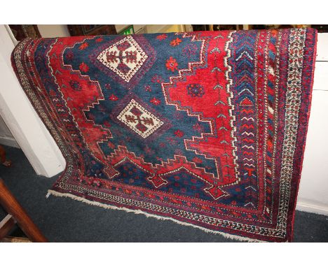 A Persian wool carpet with three-diamond centre within multi-line borders, in red, white and blue, 154cm by 200cm, (a/f - mot