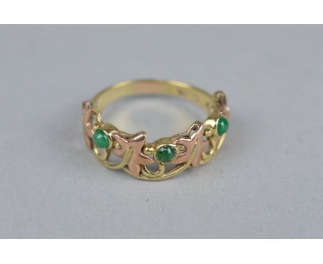 A CLOGAU EMERALD ROSE AND YELLOW METAL RING, the stylised openwork vine leaf design hand set with three cabochon cut rub over