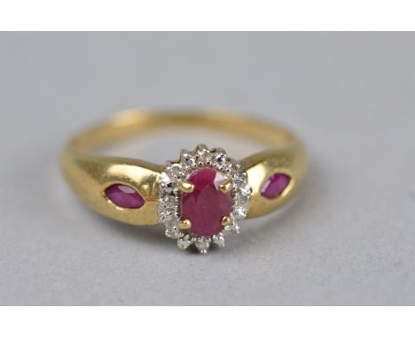 A RUBY AND DIAMOND 9CT YELLOW GOLD OVAL CLUSTER RING, the central mixed cut oval ruby measuring approximately 5.5mm x 4mm wit