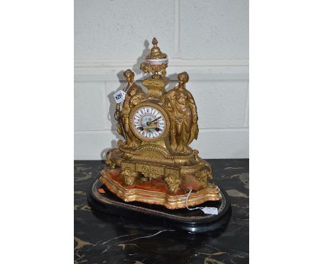 A LATE 19TH CENTURY GILT METAL MANTEL CLOCK, urn shaped finial with painted porcelain centre above the circular dial and two 