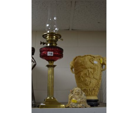 A VICTORIAN BRASS BASED COLUMN OIL LAMP, cranberry glass reservoir with chimney, lacks shade, together with a resin ivory eff