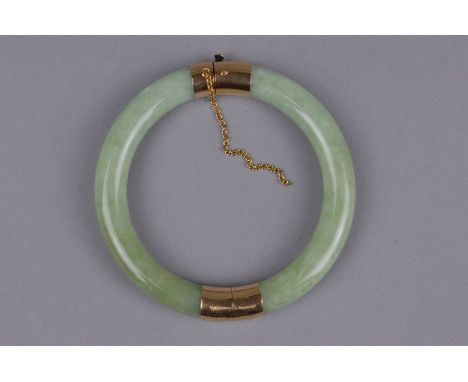 A MODERN JADE BANGLE, round hinged design with two pale green jadeite hooped sections, each capped either end in yellow metal