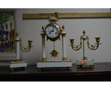 A LATE 19TH CENTURY WHITE MARBLE AND GILT METAL CLOCK GARNITURE, the clock with urn finial and bow above a circular enamel di