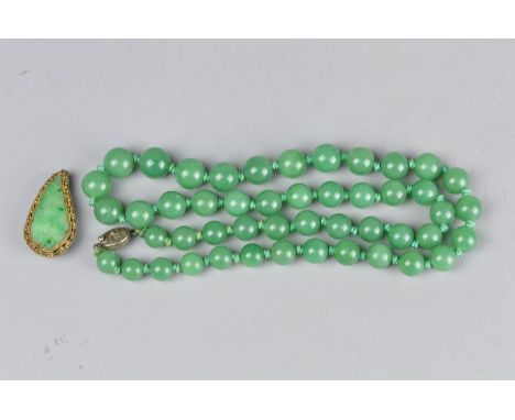 A GRADUATED JADE BEAD NECKLACE, with silver tongue snap clasp, approximate length 25 inches, together with a jade dress clip