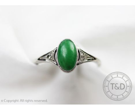 A jade and diamond ring, designed as a central cabochon jade, flanked by three rose cut diamonds to either side, all set in w