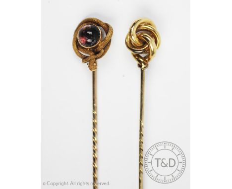 A snake stickpin, designed as a cabochon stone with entwined and coiled snake with textured finish, with a further stick pin 