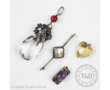 An Arts and Crafts style rock crystal and carnelian set pendant, designed as a faceted drop surmounted by white metal foliage
