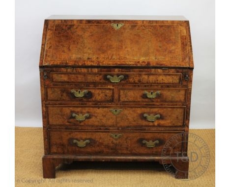 A George III and later cross banded walnut bureau, with fall enclosing a fitted interior with various drawers, alcoves and se