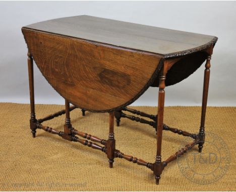 An early 20th century oak gate leg table, oval top with an oak leaf carved edge, on turned legs, 74cm H x 112cm W