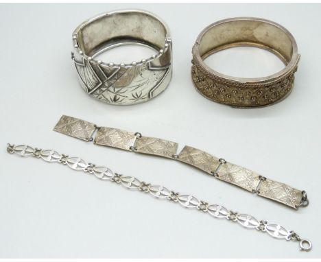 A white metal Aesthetic Movement Victorian bangle, 3.1cm wide, together with a silver bangle and two silver bracelets, three 