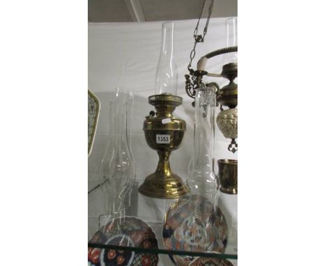 A brass oil lamp with chimney and four spare chimneys.