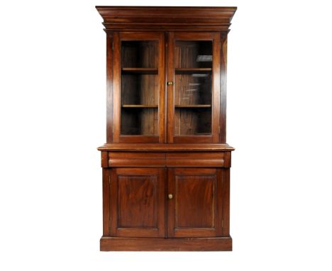 A Victorian style hardwood cabinet bookcase the moulded cornice above two glazed doors enclosing two shelves above two pulvin