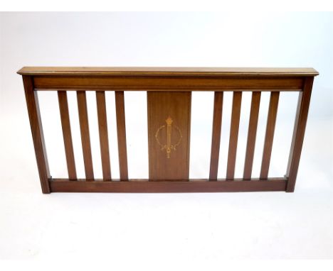 An Edwardian mahogany bed head, the central panel decorated with a marquetry inlaid flaming classical torch, flanked by splat