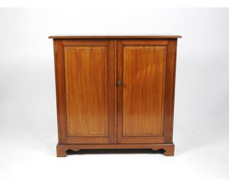 An Edwardian mahogany two door cabinet the rectangular top above two fielded panel doors enclosing two shelves and on bracket