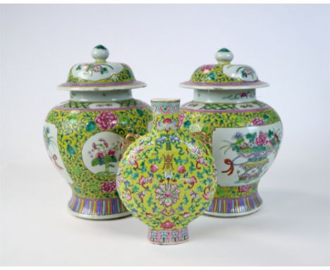 A pair of lidded Chinese porcelain famille rose jars, decorated with detailed hand-painted vignettes of porcelain vases laden