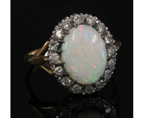 An 18ct gold opal and diamond oval cluster ring,with an oval cabochon opal, claw set to the centre. A border of brilliant cut