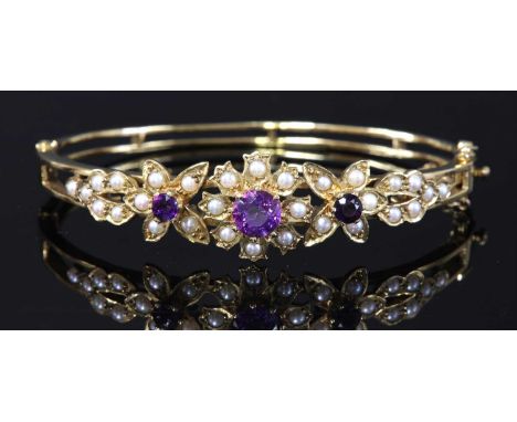 A 9ct gold amethyst and split cultured pearl hinged bangle, c.1970,the top half composed of three graduated flower head clust
