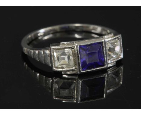 An Austrian Art Deco three stone synthetic sapphire and diamond ring,with a square cut synthetic sapphire, milligrain set to 