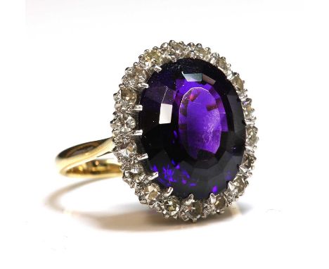 An amethyst and diamond oval cluster ring,with an oval step cut amethyst, claw set to the centre. A border of eight cut diamo