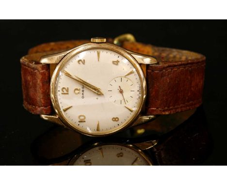 A gentlemen's 9ct gold Omega mechanical strap watch, c.1960,with a 34mm engraved case. A silvered dial with alternating gilt 