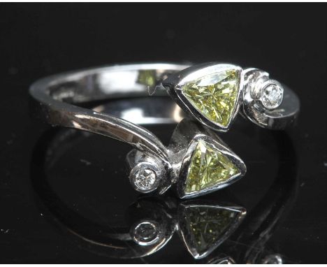 An 18ct white gold four stone diamond crossover ring,with two trilliant cut diamonds, possibly fancy light yellow, with a sta