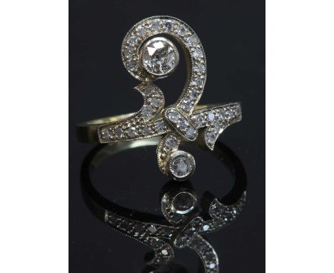 An Art Nouveau-style diamond set ring,with a scrolling head and shoulders, milligrain set with two graduated old Swiss cut di