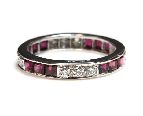 An 18ct white gold ruby and diamond full eternity ring,with alternating sections of three channel set calibré rubies, between
