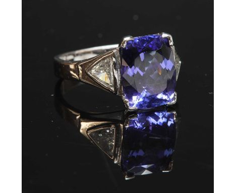 An 18ct white gold single stone tanzanite ring,with diamond set shoulders. A cushion cut tanzanite with a stated weight of 4.