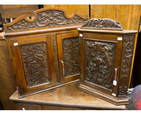 An oak hanging corner cupboard fitted with a single door with carved panel in high relief, together with a further two door w