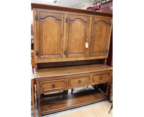 A George I style oak dresser the upper section with three doors opening to reveal fitted shelves the base section fitted with
