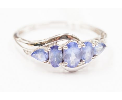 A white gold five stone tanzanite ring of graduated oval and pear shape tanzanite, stamped 14k 