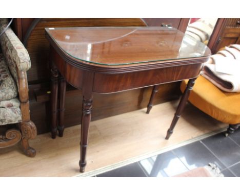 A George III mahogany card table, raised on turned tapering legs
