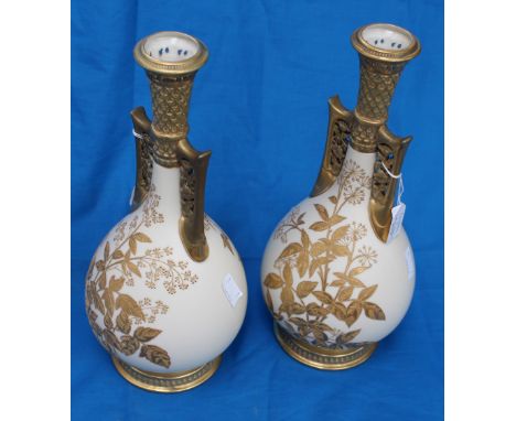 A pair of Royal Worcester bulbous twin handled vases in ivory, enamelled with gold 