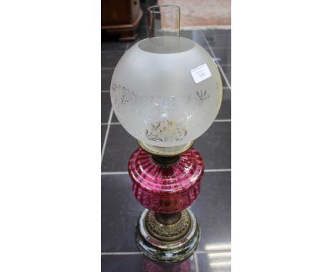 A Victorian brass based oil lamp with a cranberry reservoir and an opaque white shade, with funnel