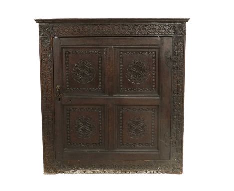 An 18th Century Joined Oak Cupboard, with carved frieze and stiles above a moulded cupboard door with four fielded panels car